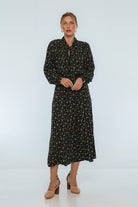 Woman wearing a black floral midi dress on a white background