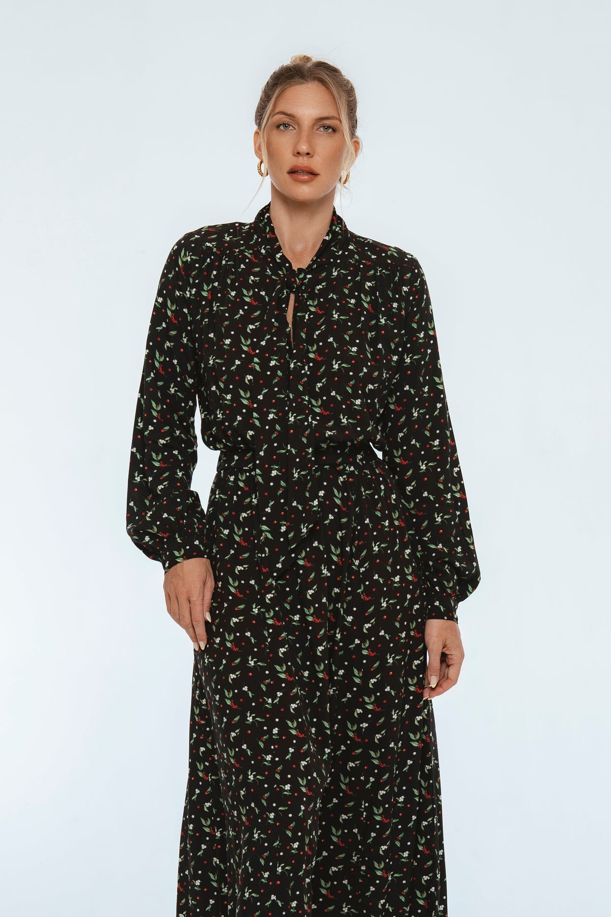 Woman wearing a black floral dress on a light gray background