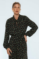 Woman wearing a black floral dress against a light blue background