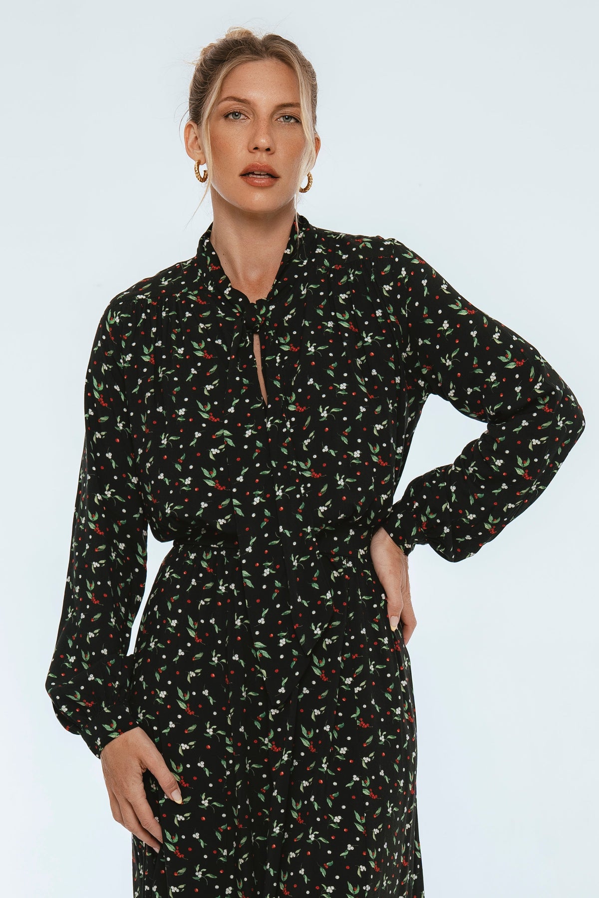 Woman wearing a black floral dress against a light blue background