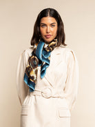 Woman wearing a patterned scarf around her neck against a beige background