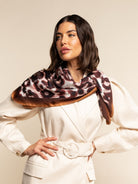 Woman wearing a patterned silk scarf on a beige background