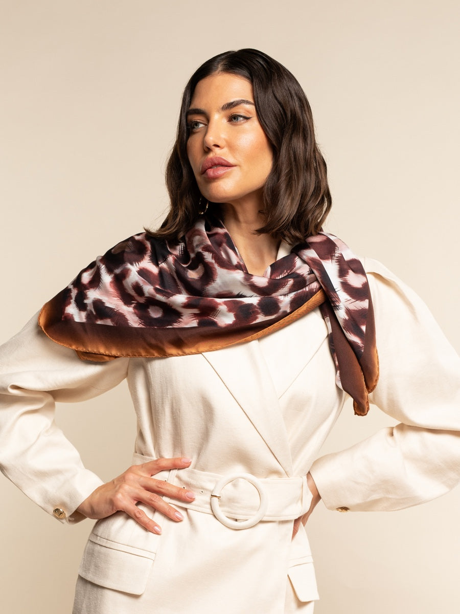 Woman wearing a patterned silk scarf on a beige background