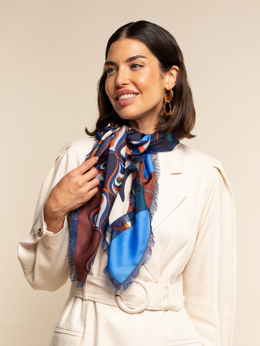 Woman wearing a colorful silk scarf around her neck against a beige background
