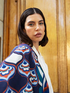 Woman wearing a patterned jacket in front of a wooden door