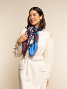 Woman wearing a colorful scarf around her neck against a plain background