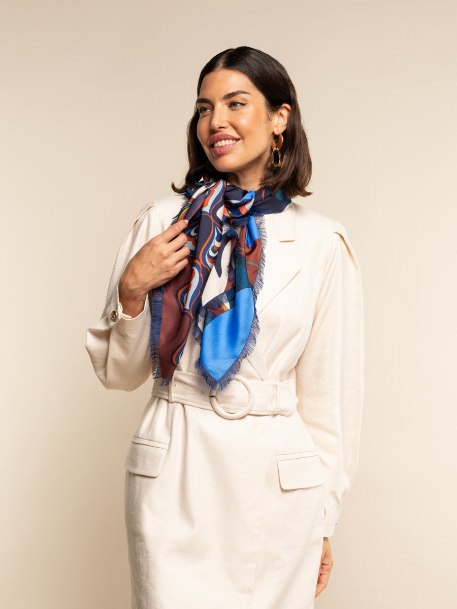 Woman wearing a colorful scarf around her neck against a plain background