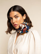 Woman wearing a colorful silk scarf around her neck against a beige background