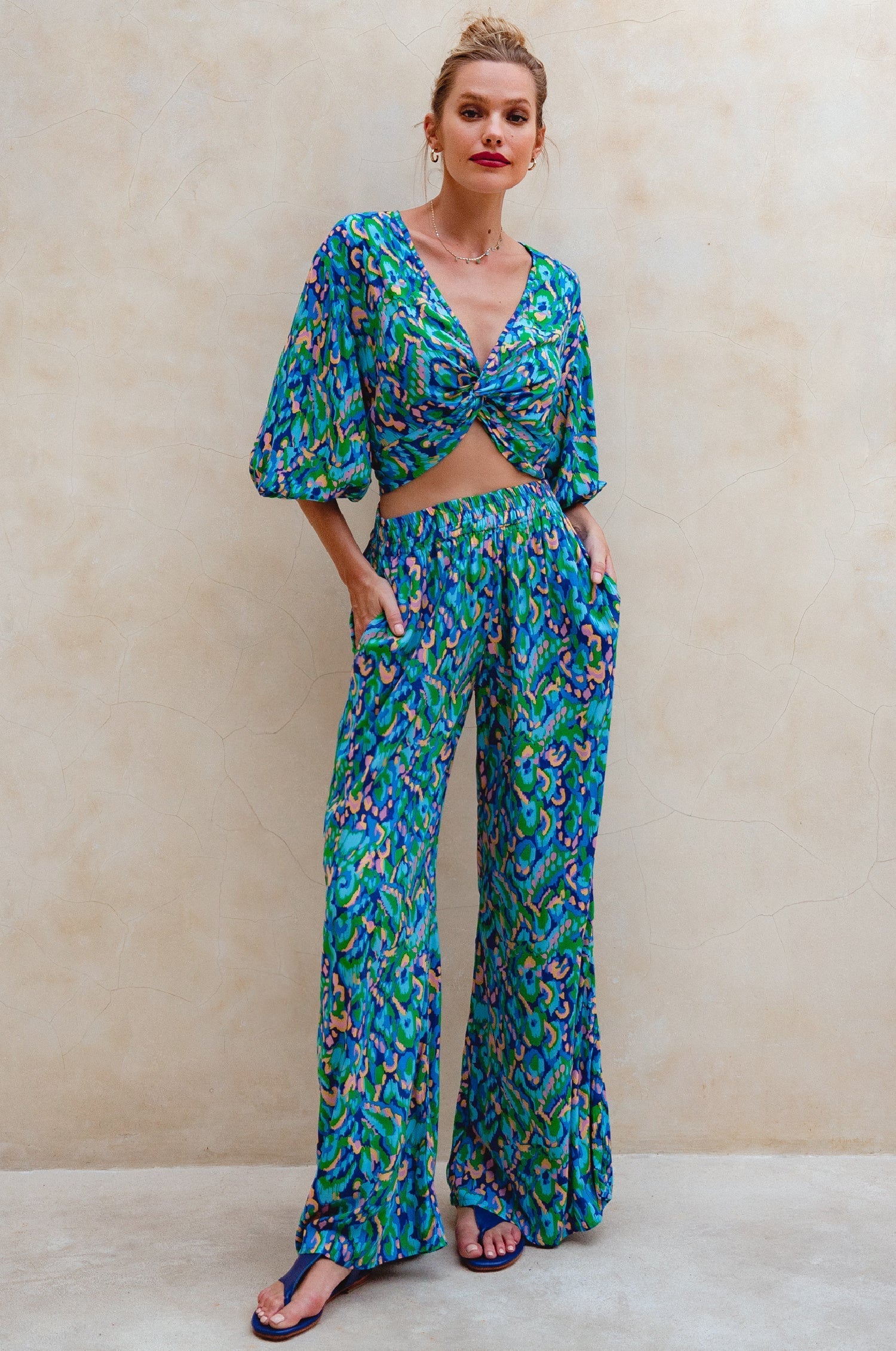 Woman wearing a green floral outfit against a beige background