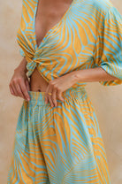 Person wearing a yellow and blue patterned outfit against a beige background