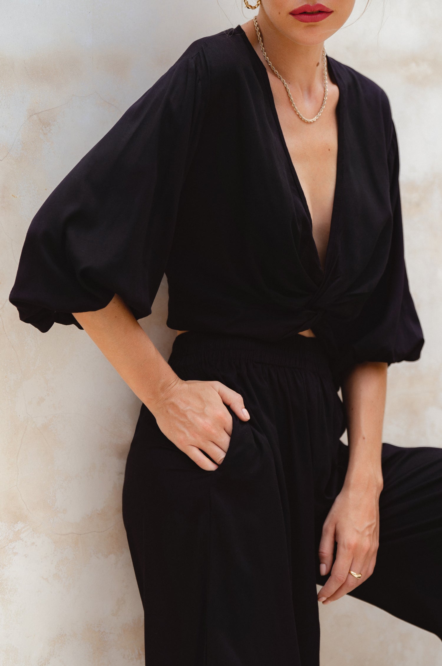 Person wearing a black outfit with puffed sleeves against a light background