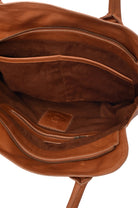 Close-up of a tan suede lined interior of a tan leather bag with visible stitching and brand logo.