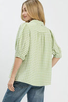 Woman wearing a green checkered shirt and blue jeans on a white background