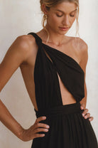 Woman wearing a black multi-way tie halter neck jumpsuit against a plain background, closeup of halter