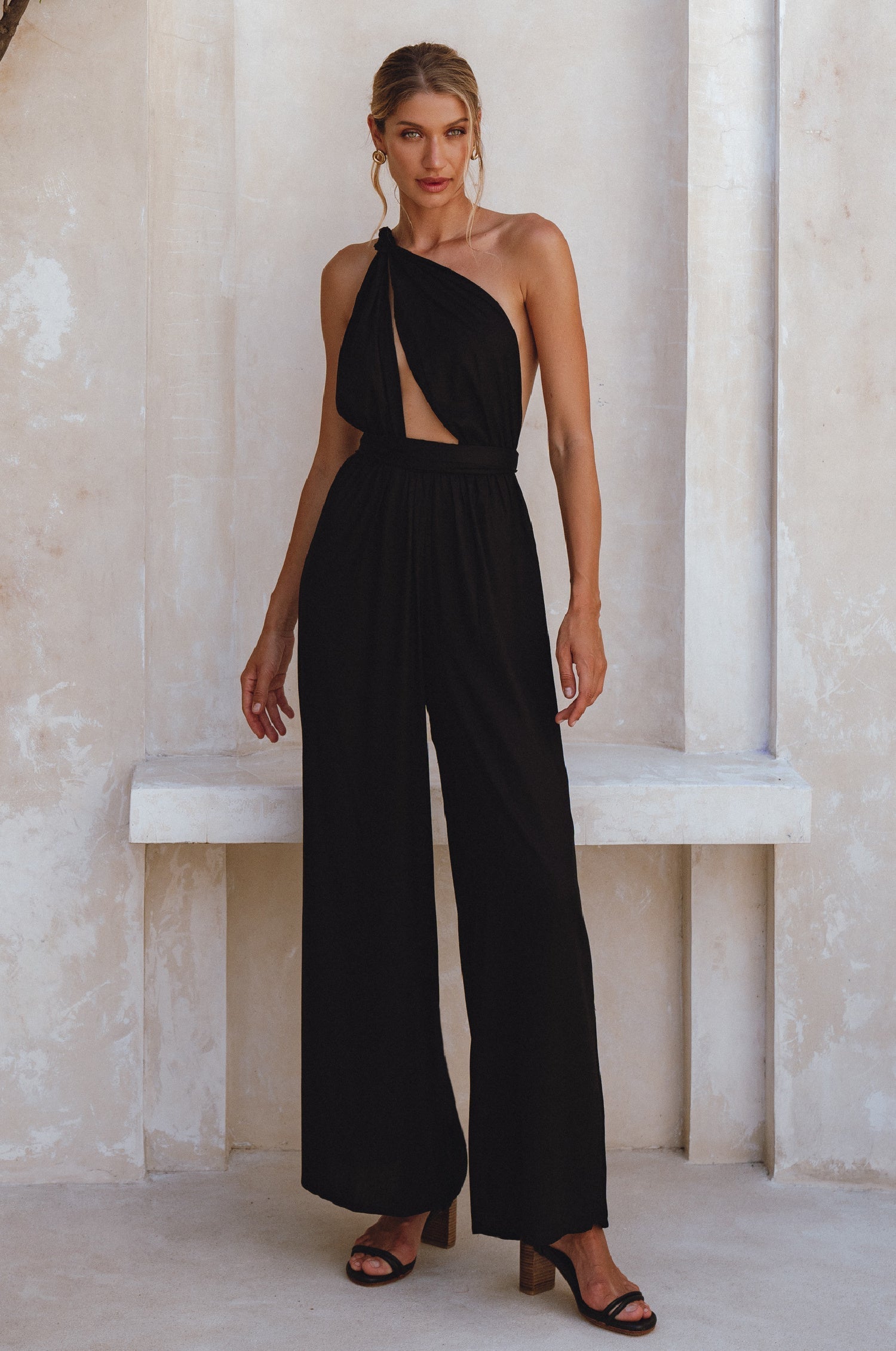 Woman wearing a black jumpsuit with a cutout design in a neutral setting