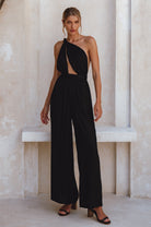 Woman wearing a black jumpsuit with a cutout design in a neutral setting
