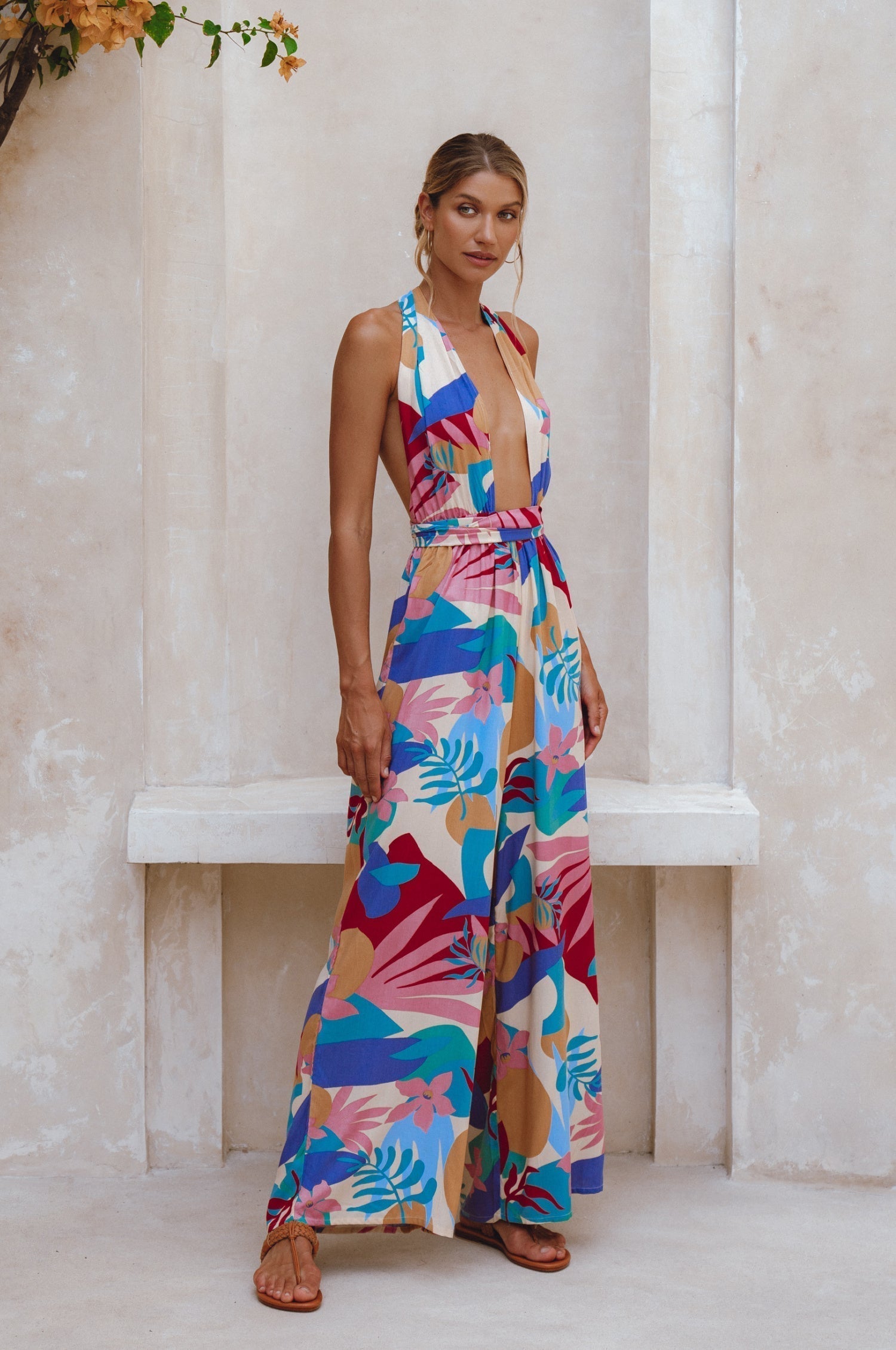 Woman wearing a colorful patterned jumpsuit standing in front of a bench.
