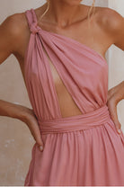 Pink one-shoulder jumpsuit with a tie detail on a neutral background, closeup of the bodice and the open halter with multi-way ties