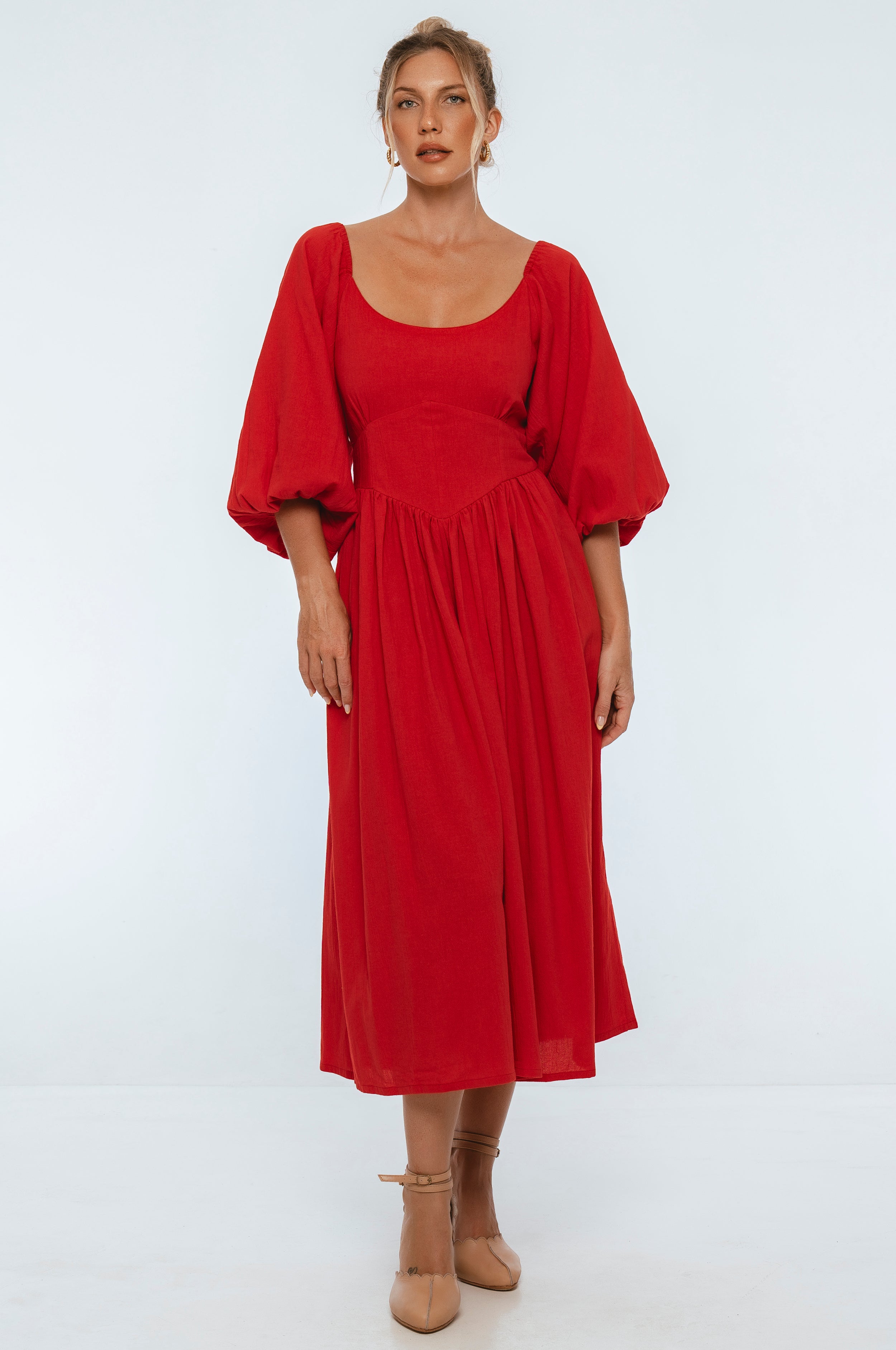 Woman wearing a red midi dress with puff sleeves on a white background