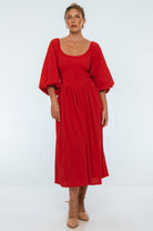 Woman wearing a red midi dress with puff sleeves on a white background