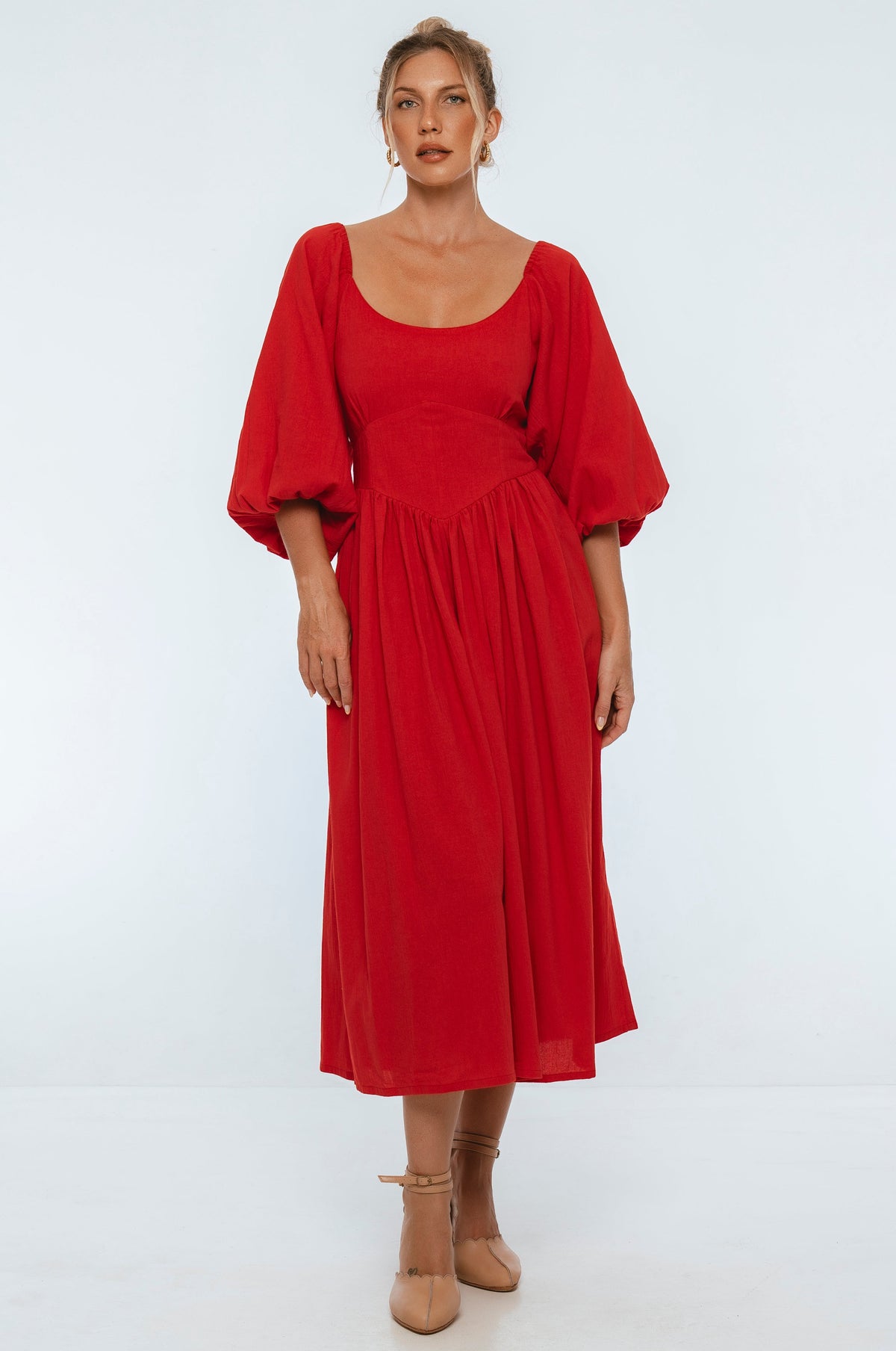 Woman wearing a red midi dress with puff sleeves on a white background