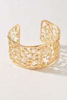 A gold-toned openwork cuff bracelet with an intricate leafy filigree pattern, photographed on a clean white background.