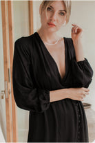 Woman wearing a black dress with a deep neckline indoors.