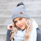 gray boucle knit hat with faux fur pom worn with scarf, angled view