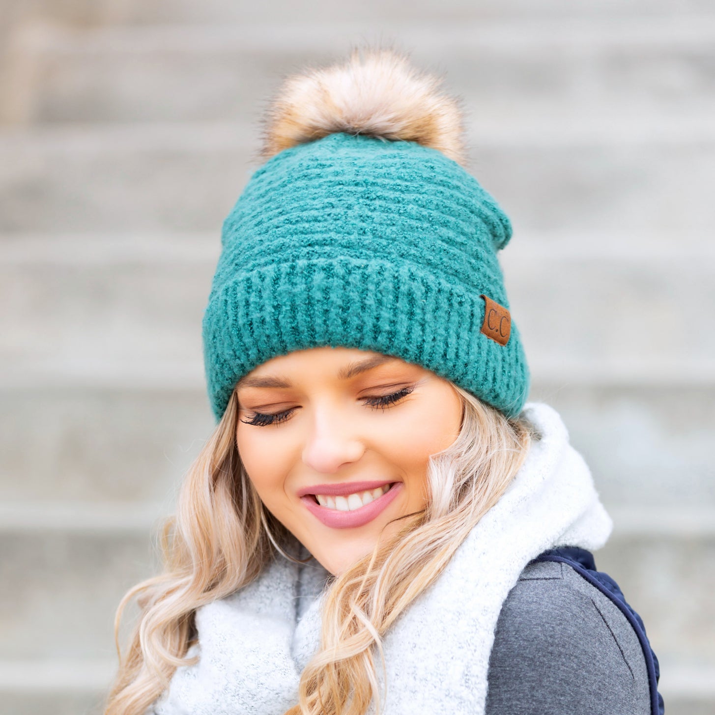 green boucle knit hat with faux fur pom worn with scarf, angled view