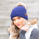 Evening Blue boucle knit hat with faux fur pom worn with scarf, angled view