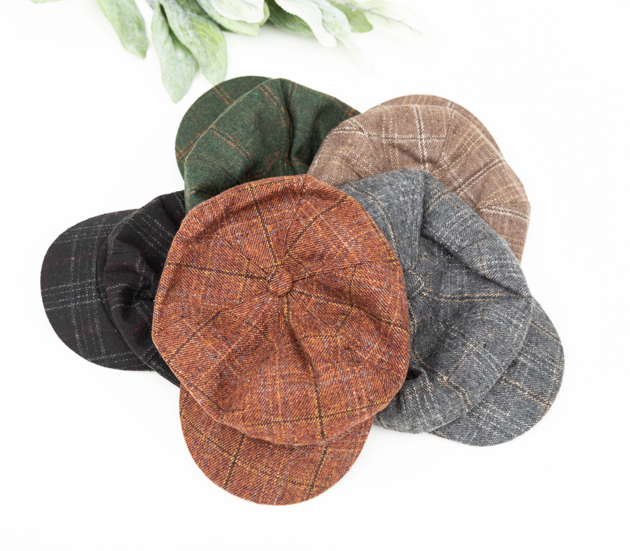 Five patterned baker boy caps in hunter green, brown, black, rust, and gray on a white background.