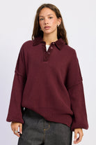 The Weekend Club Collared Knit Sweater in burgundy with ribbed polo collar, button neckline and relaxed oversized fit, front view.