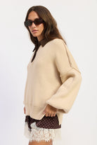 Side view of oatmeal collared knit sweater showing relaxed fit, dropped shoulders and side slit hem.