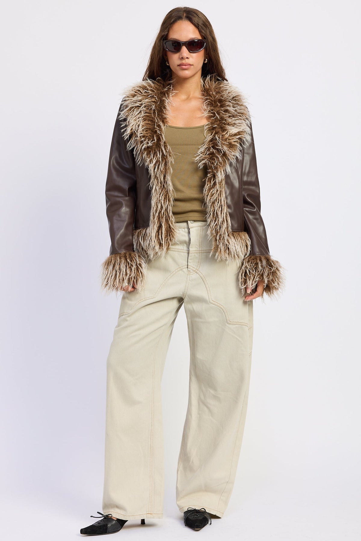Brown faux leather jacket with contrasting brown and cream shaggy faux fur trim, styled with wide leg cream jeans.