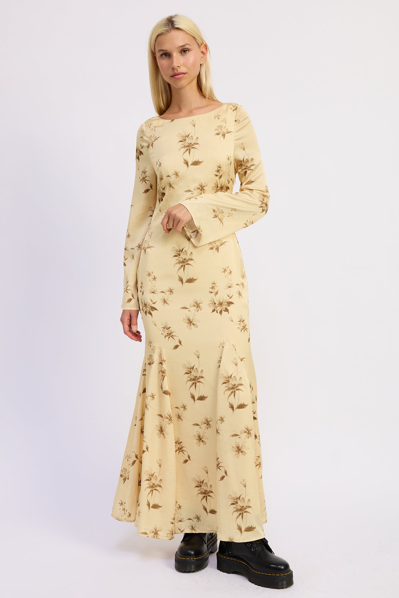 Woman wearing a long-sleeve, floral-patterned maxi dress on a white background