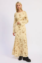 Woman wearing a long-sleeve, floral-patterned maxi dress on a white background