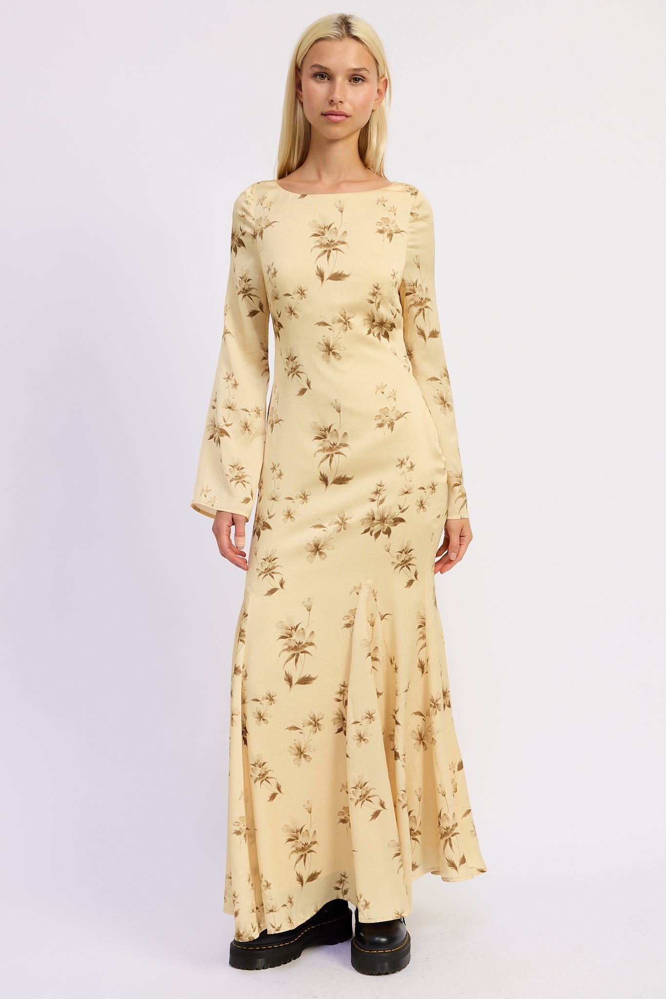 Woman wearing a long-sleeve, floral-patterned maxi dress on a white background
