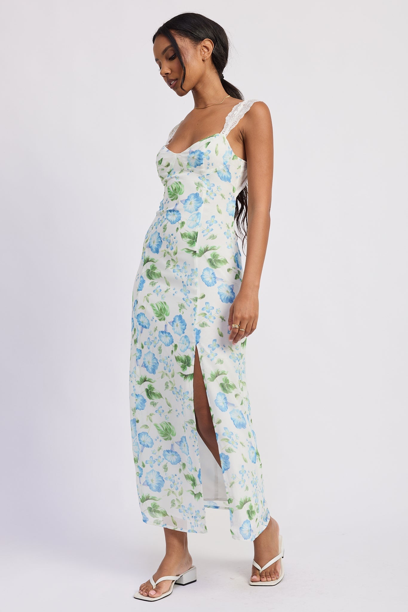 Side view of blue floral chiffon maxi dress showing front slit and fitted silhouette, AVAH