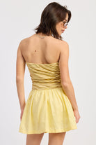 Woman wearing a yellow strapless mini dress striped bodice contrast skirt on a white background 
