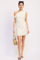 Woman wearing an ivory one-shoulder mini dress against a white background front view