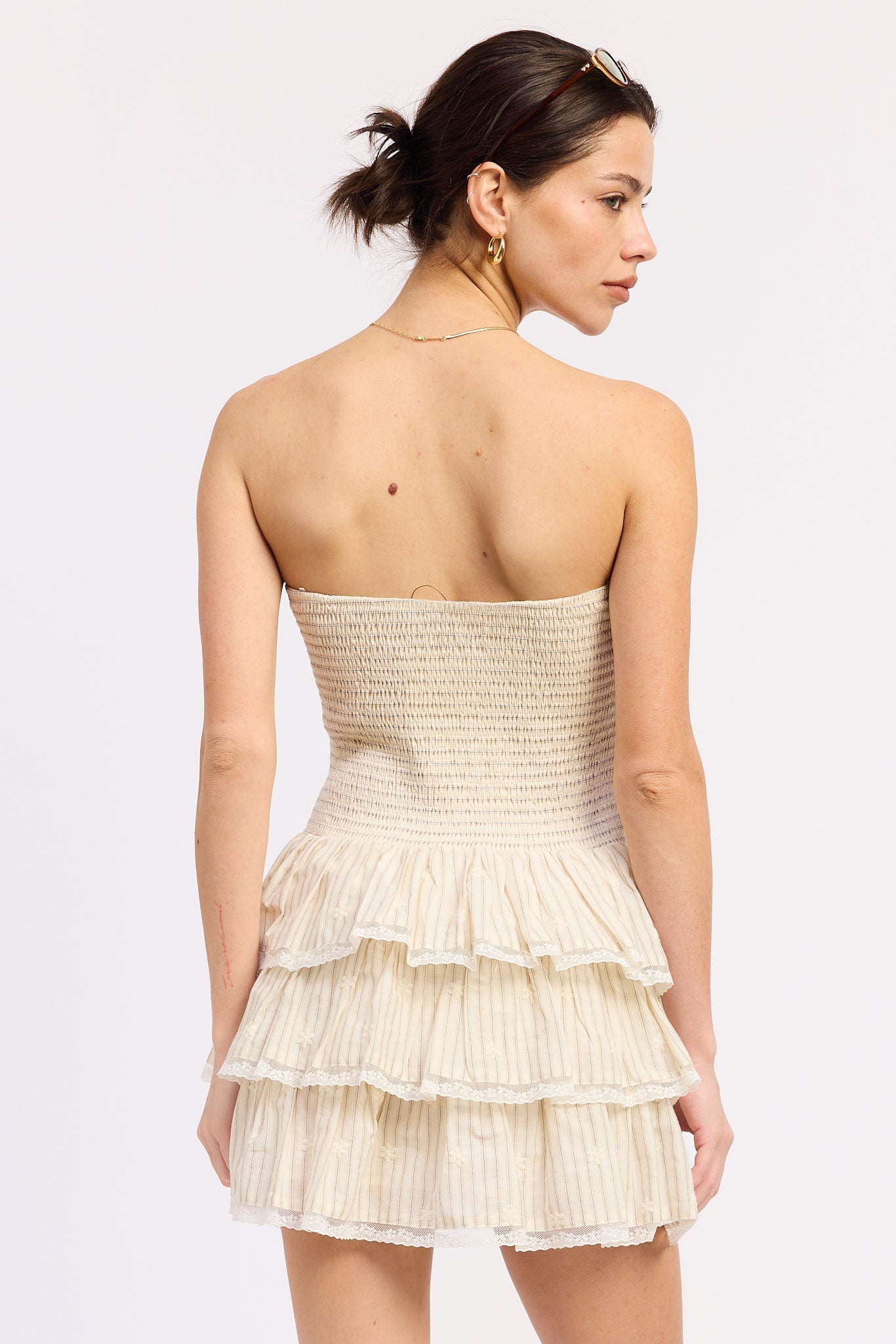 woman wearing cream strapless smocked tiered mini dress front view on white background back view 