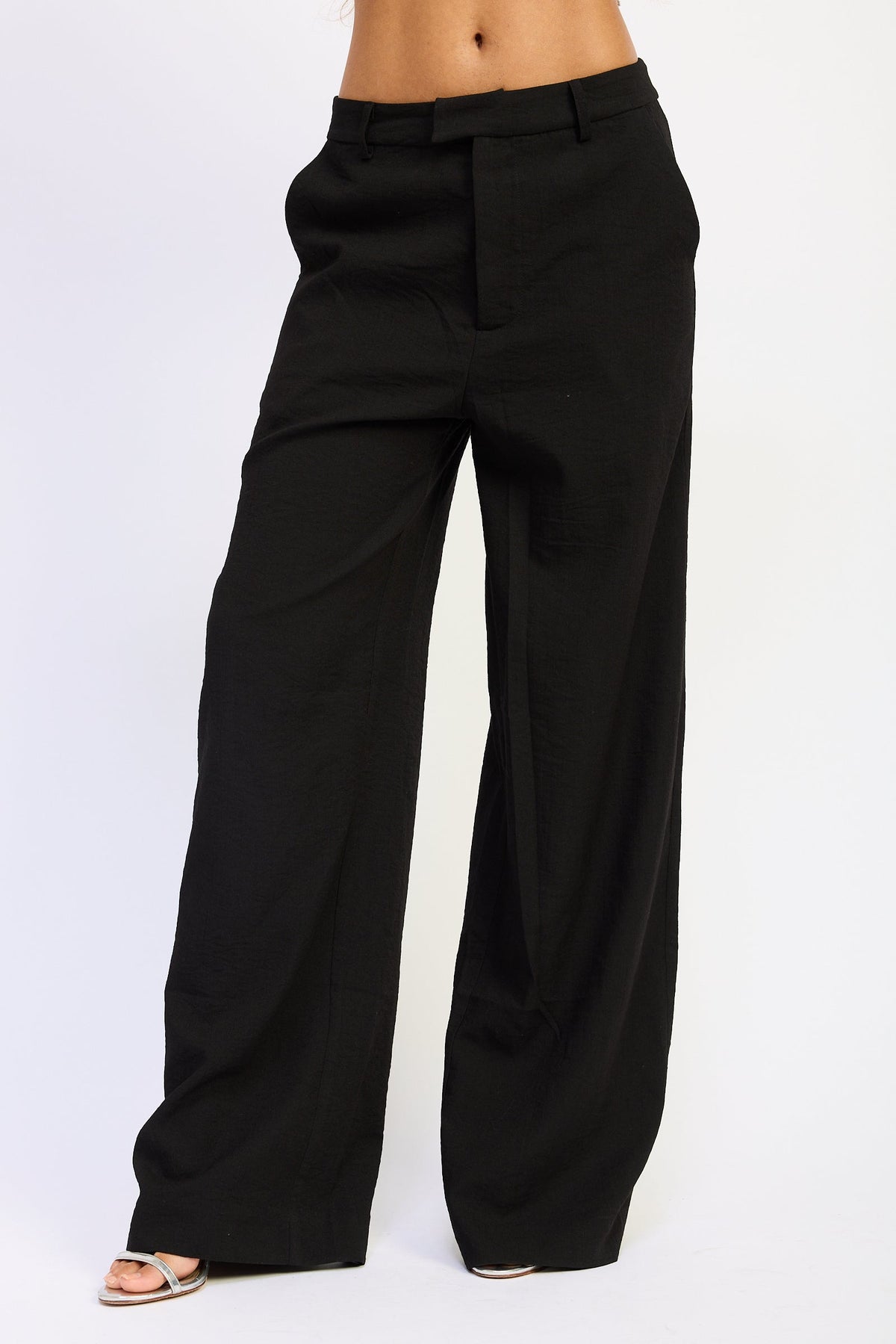 Close front view of Marlowe Black Wide Leg Pants showing waistband, belt loops, front pleats and wide leg design.