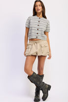 Full length view of Varsity Lines striped short sleeve cardigan in Heather Grey Combo styled with khaki mini skirt and knee high boots. 