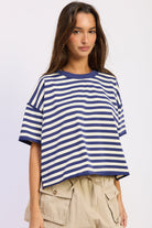 Woman wearing a blue and white striped shirt with light blue jeans on a plain background