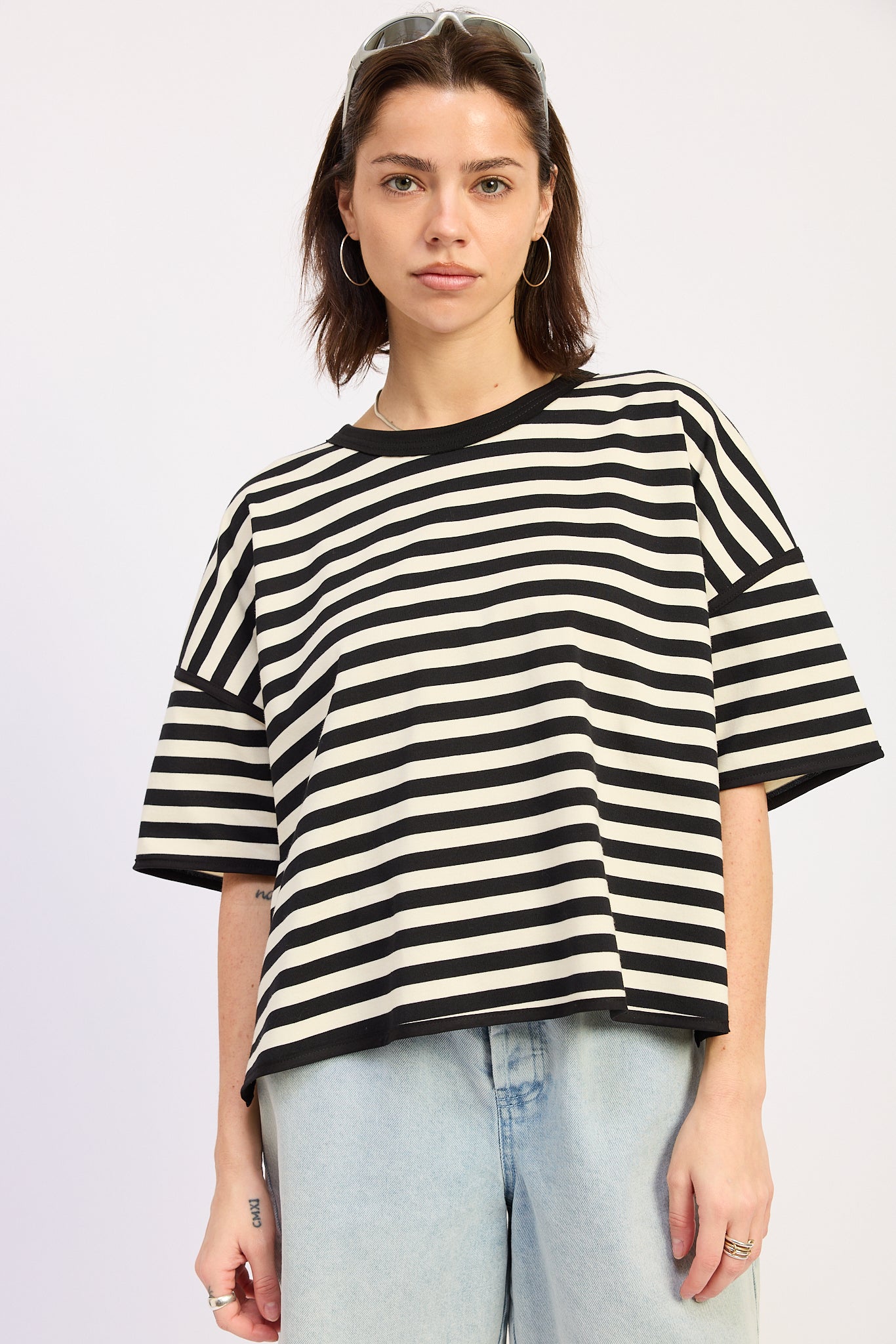 Woman wearing a black and white striped shirt with light blue jeans on a plain background