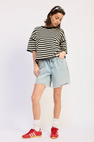 Woman wearing a black and white striped shirt with light blue jeans on a plain background
