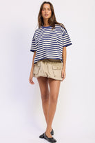 Woman wearing a blue and white striped shirt with light blue jeans on a plain background