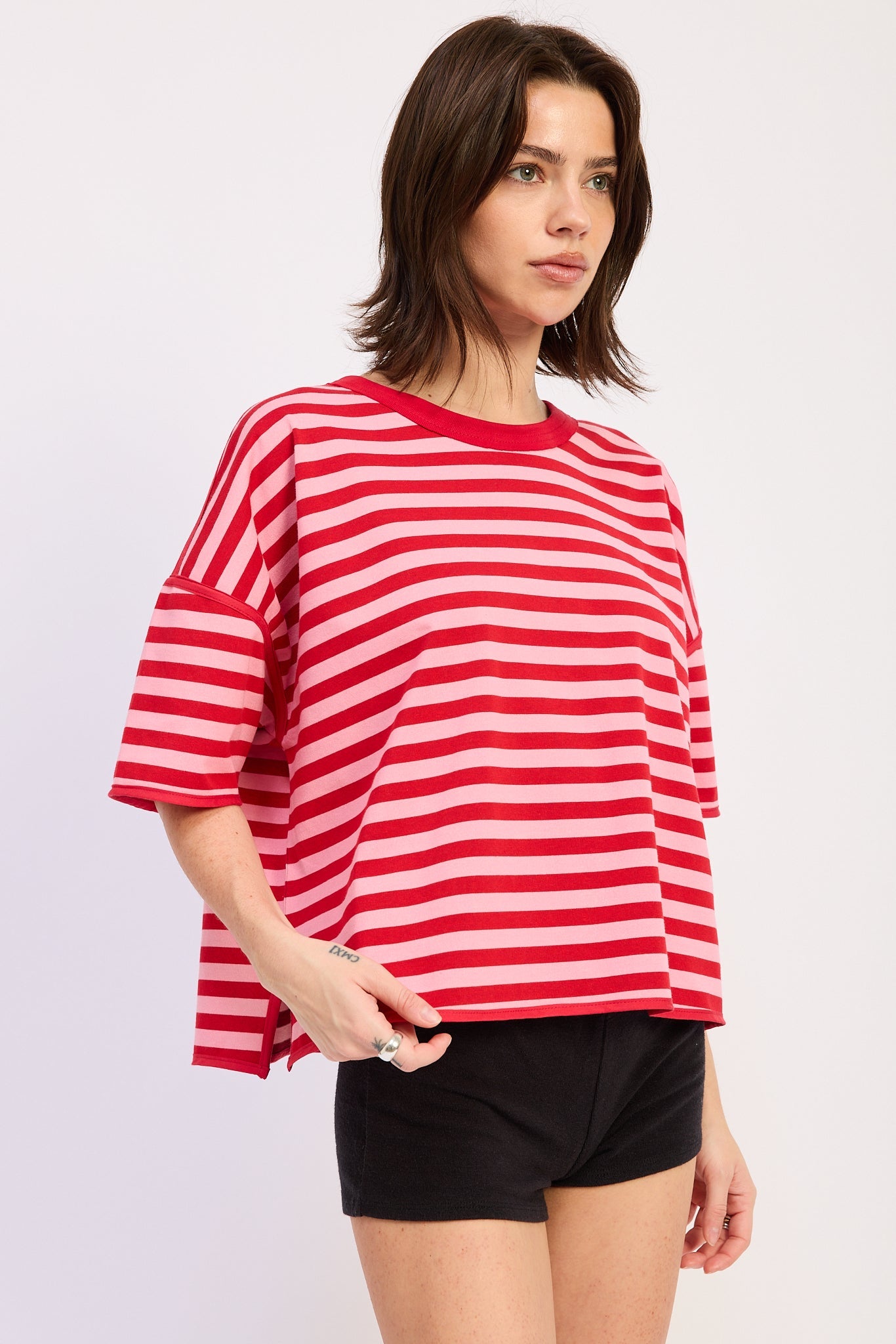 Woman wearing a red and pink striped shirt with light blue jeans on a plain background
