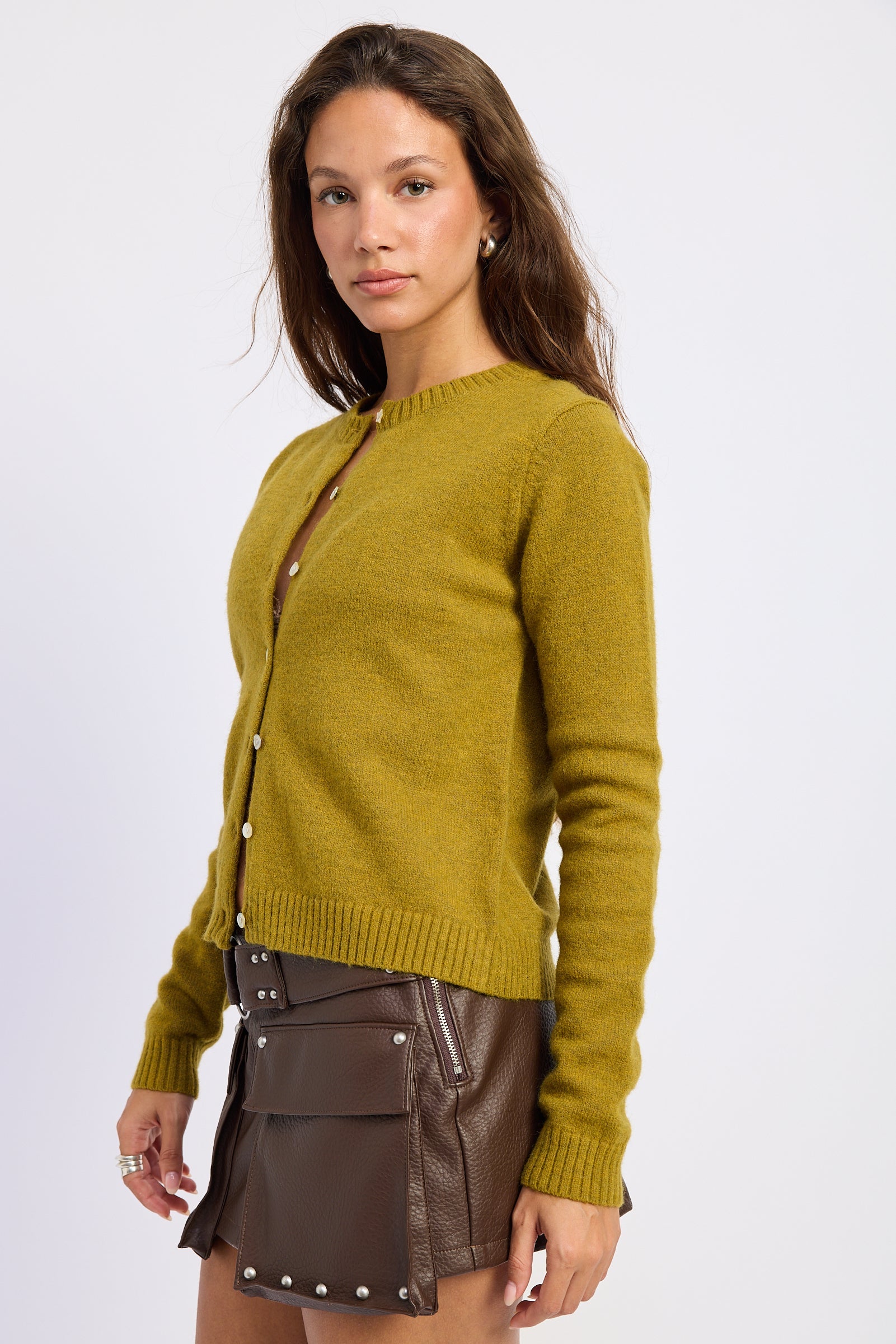 Side view of moss green button front cardigan showing the close fitting silhouette and ribbed hem.