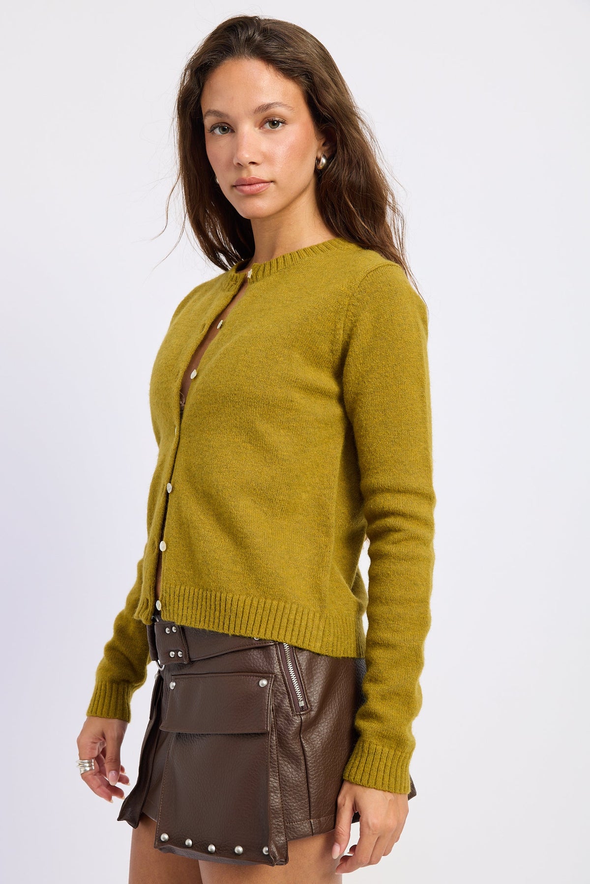 Side view of moss green button front cardigan showing the close fitting silhouette and ribbed hem.